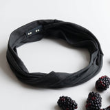 KOOSHOO organic twist headband in jet black off-packaging with fresh black berries scattered around #color_jet-black
